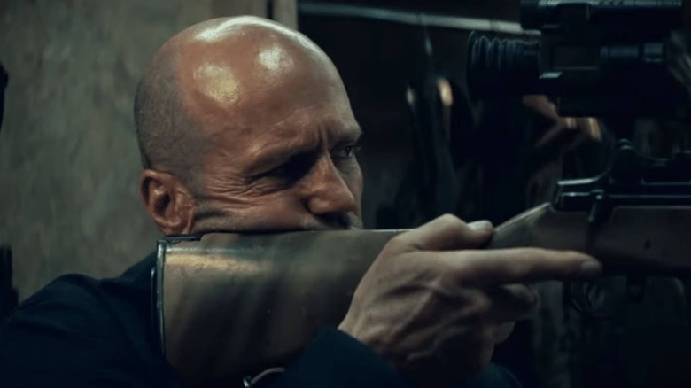 Levon Cade holding a sniper rifle in A Working Man